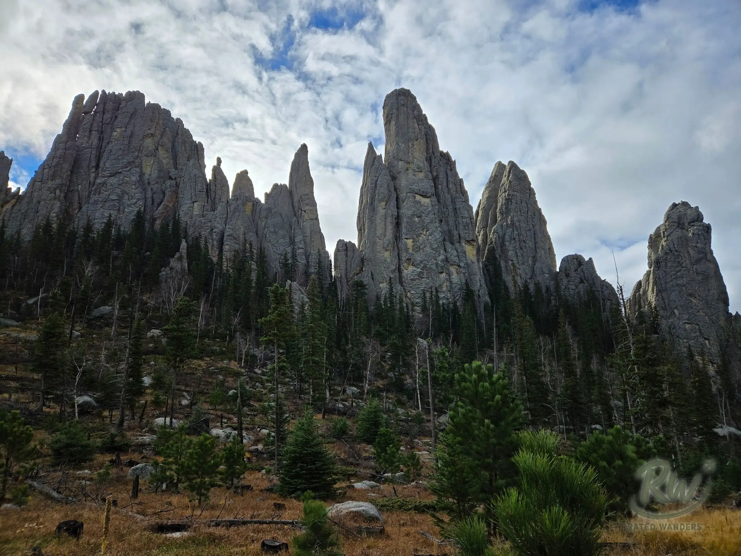 Tall granite spires rising over dark pines beneath a cloudy sky