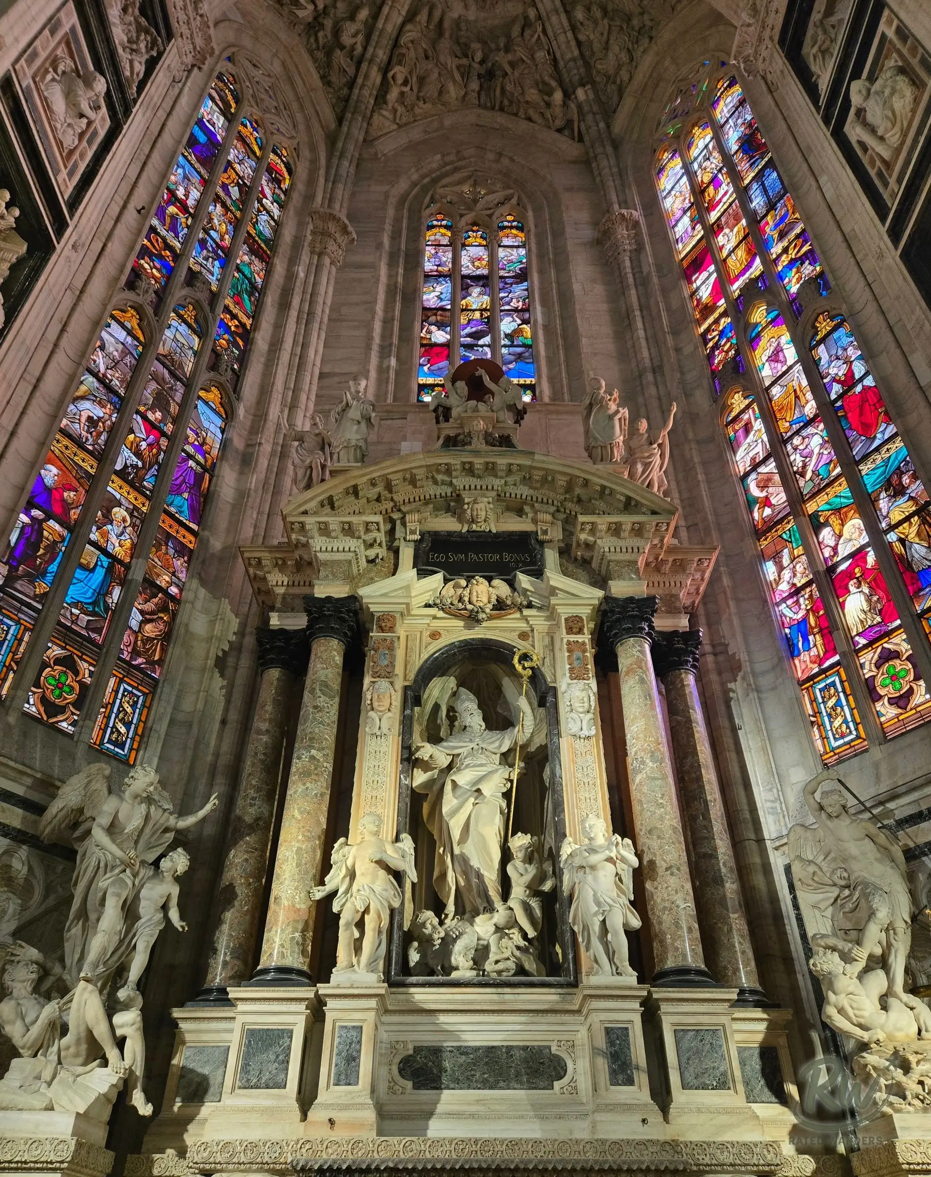 A marble altar inside the Duomo flanked by tall stained glass windows