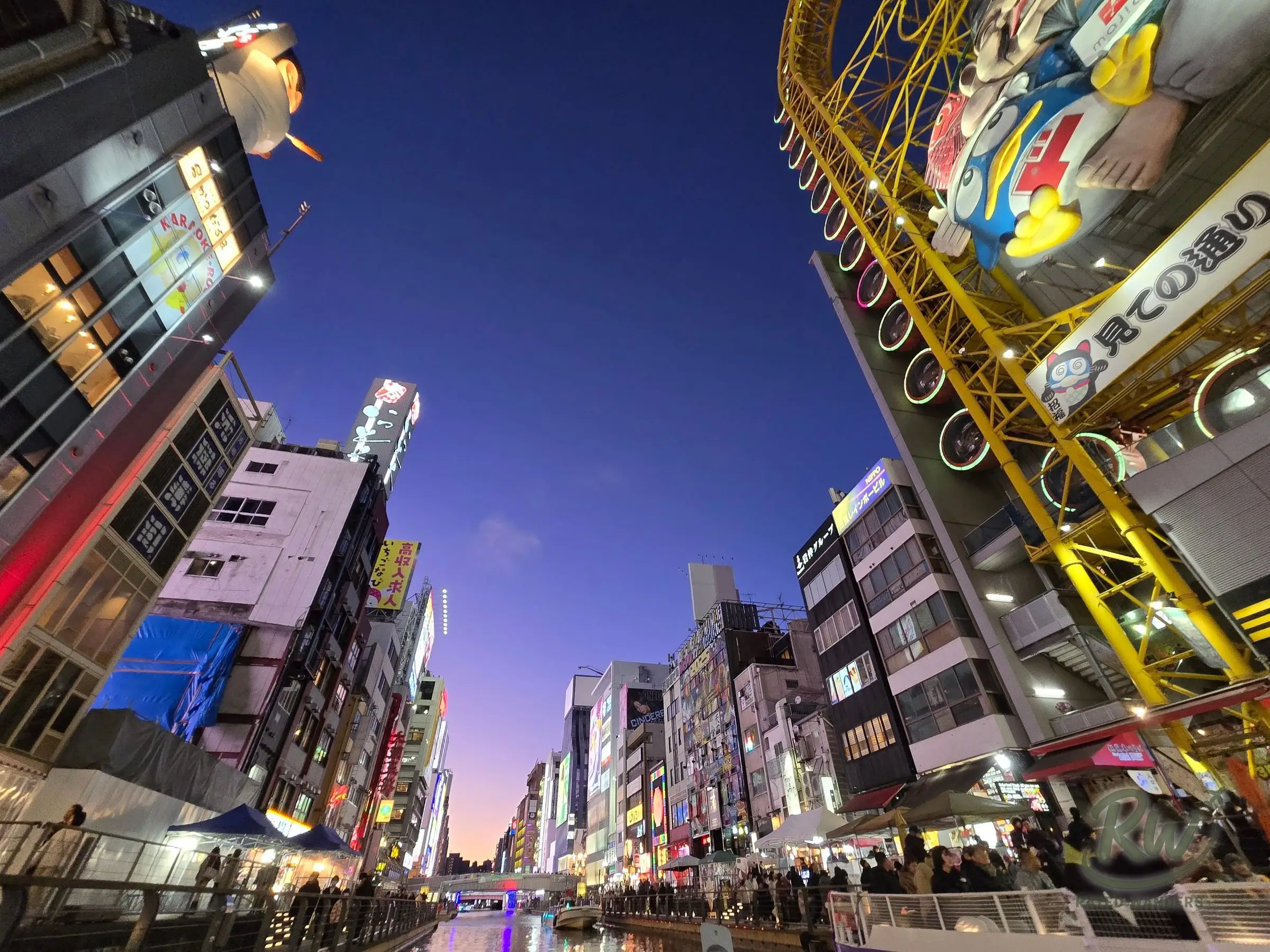The Dotonbori canal at dusk, a purple sky above neon-lit buildings and the Don Quijote Ferris wheel