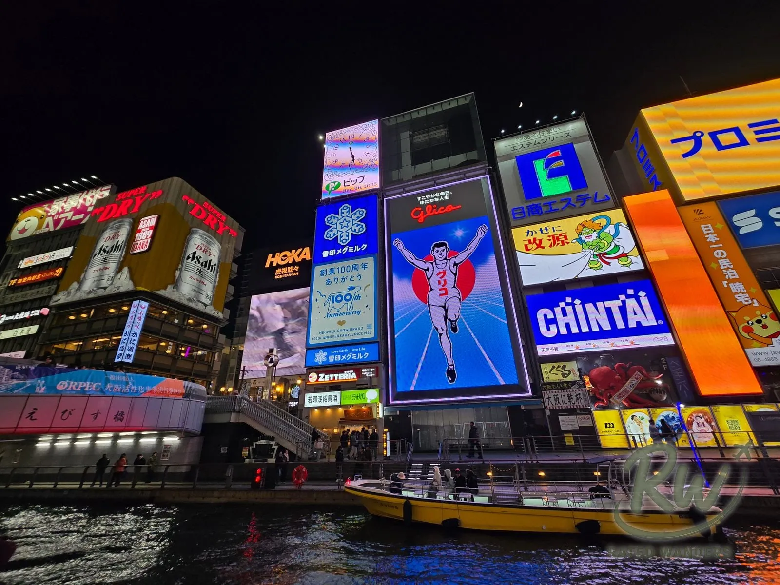 The Glico running man billboard lit up above the Dotonbori canal at night