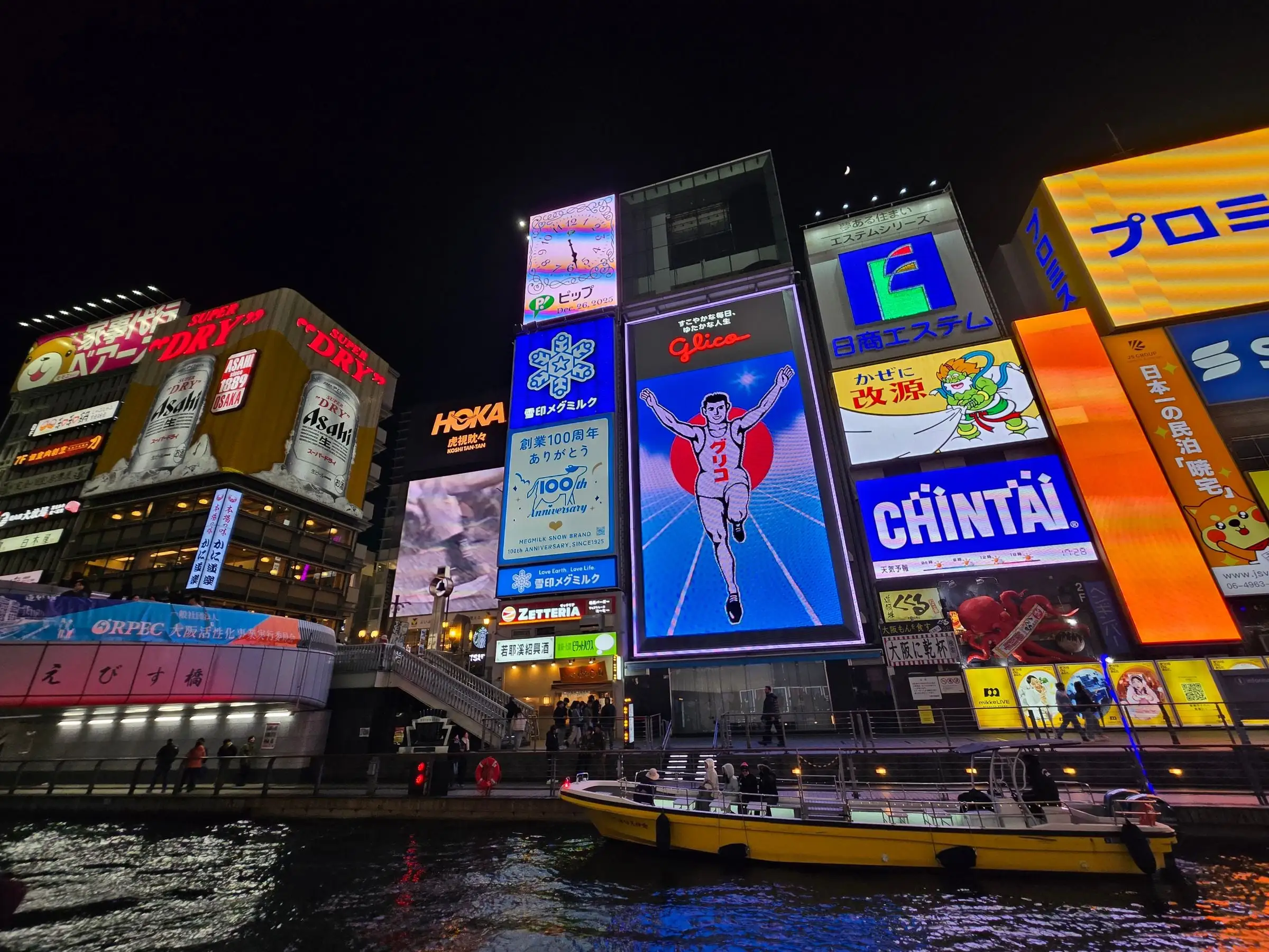 The Glico running man billboard lit up above the Dotonbori canal at night