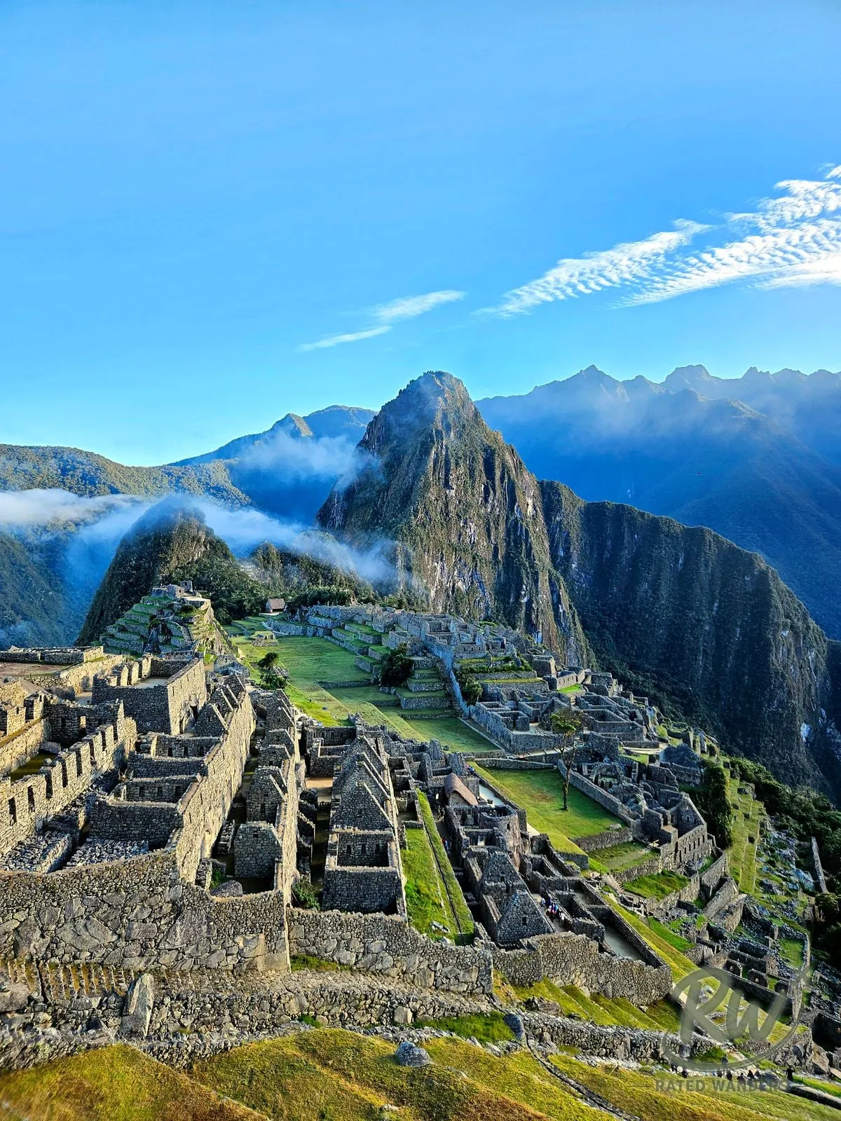 Machu Picchu’s stone terraces below Huayna Picchu, with morning cloud in the valley.