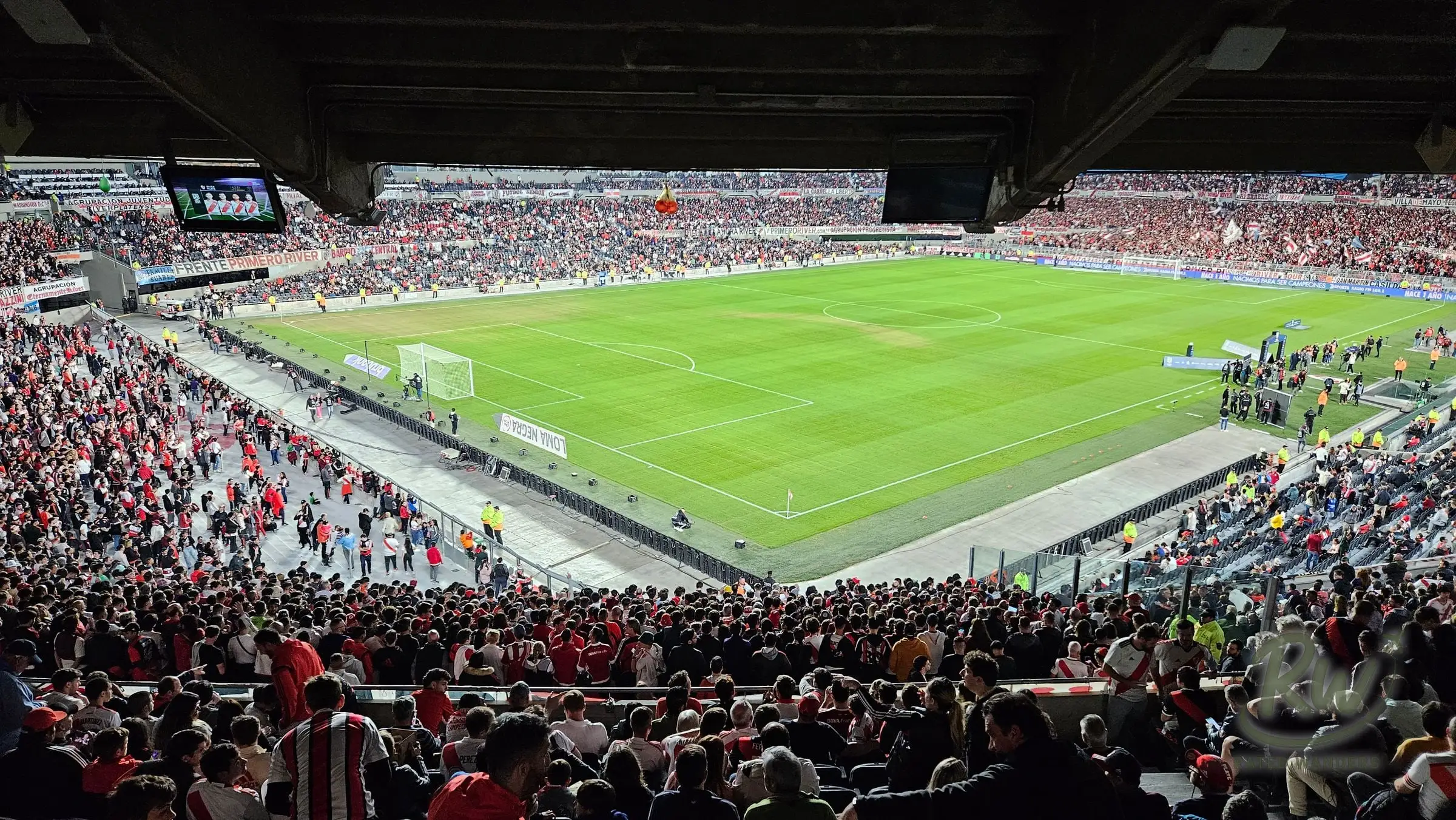 The pitch and far stands seen from under the upper deck, crowd filling the tier below